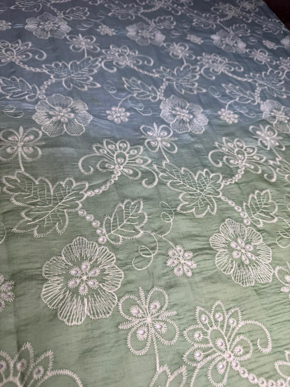 Embroidered fabric with floral patterns on a green background