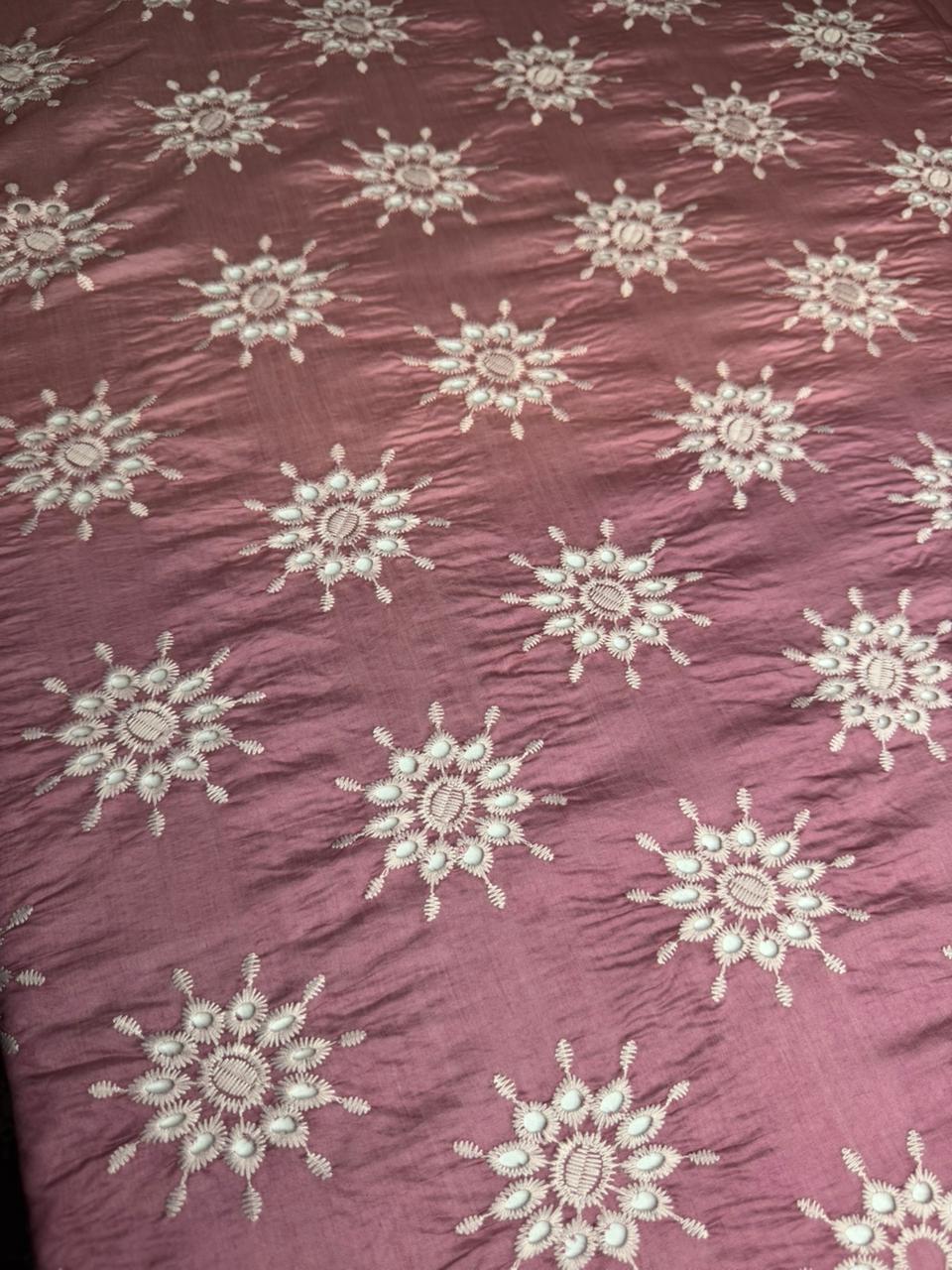 Patterned fabric with snowflake designs on a maroon background