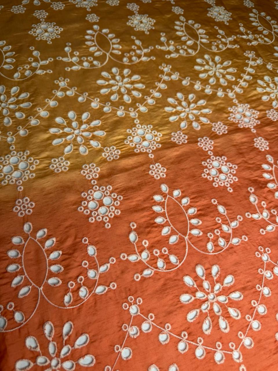 Textile with white floral patterns on a gradient orange and brown background