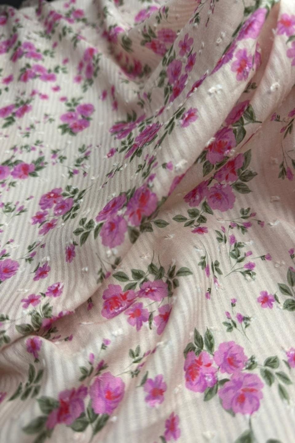 Floral fabric with pink flowers and green leaves on a light background