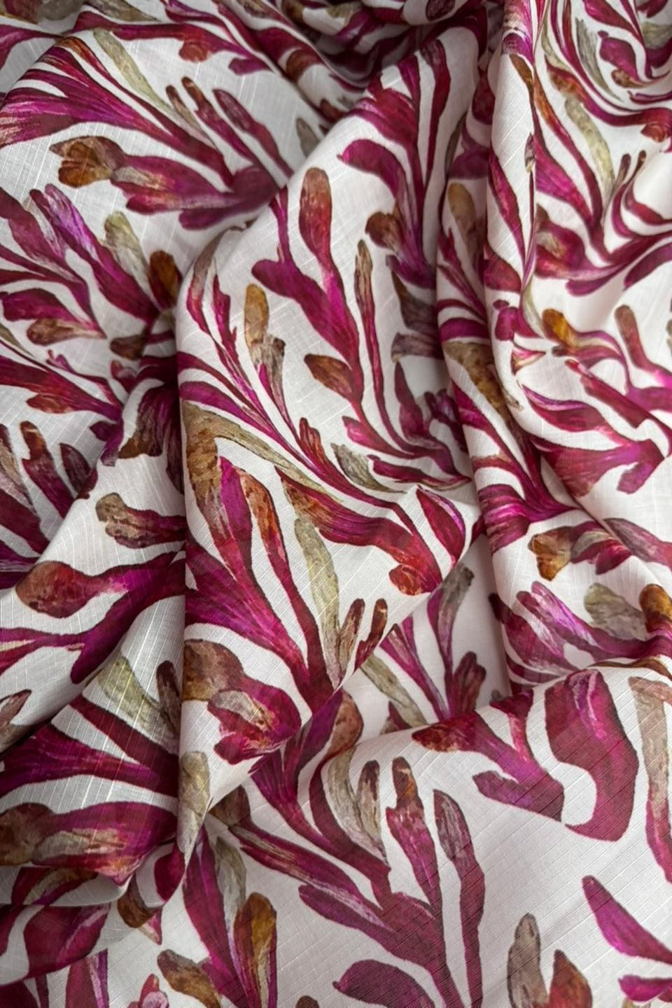 Close-up of fabric with red and brown abstract pattern on white background