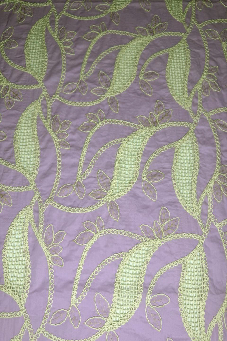 Embroidered fabric with green leaf pattern on a purple background