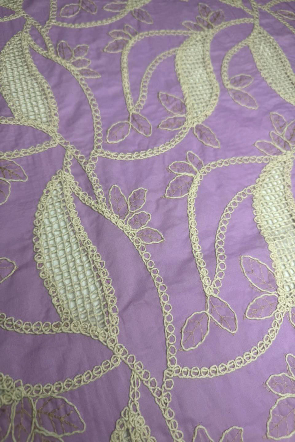 Embroidered fabric with green leaves on a purple background