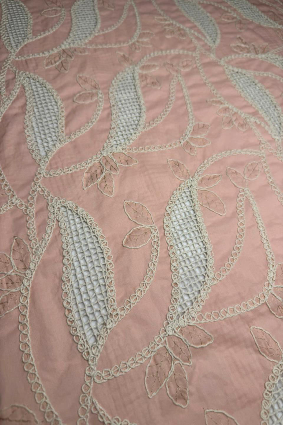 Close-up of pink fabric with intricate white embroidery
