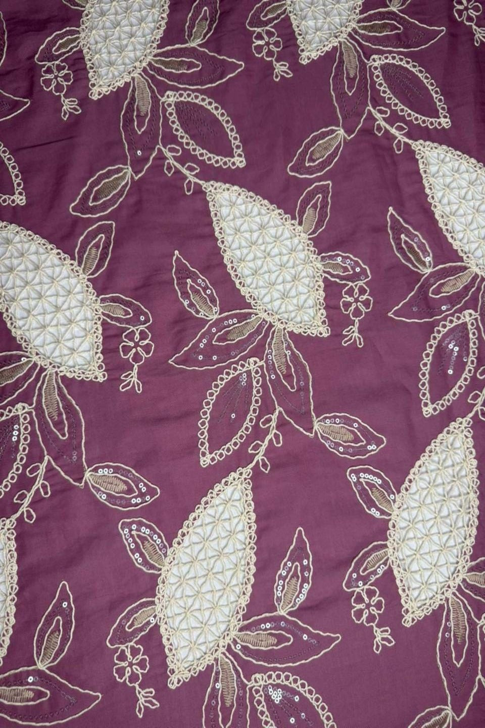 Close-up of a fabric with intricate white floral patterns on a purple background