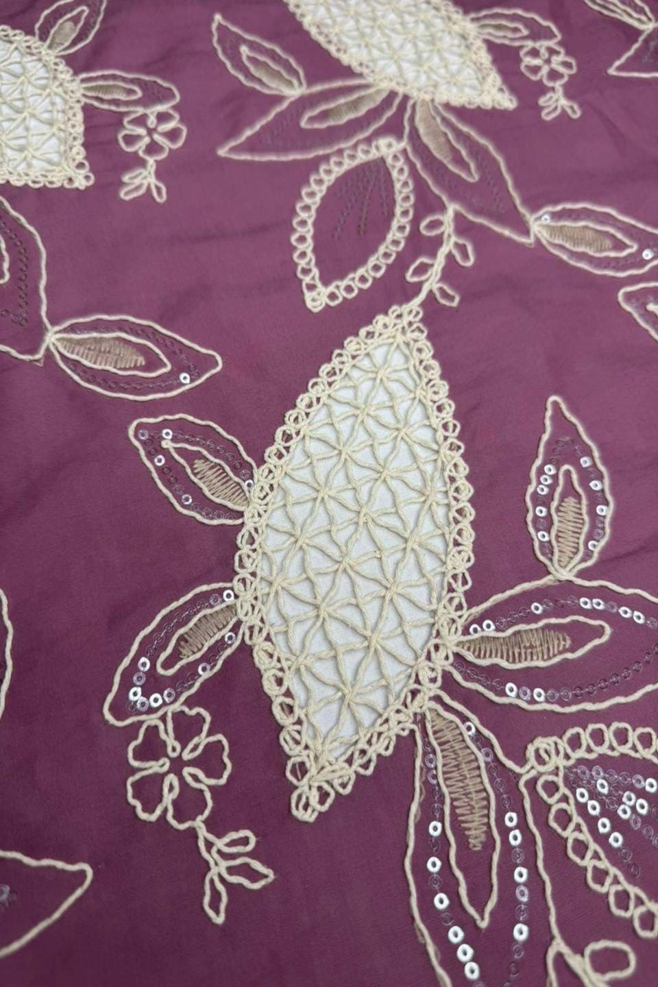 Close-up of a purple fabric with gold embroidery and sequins.