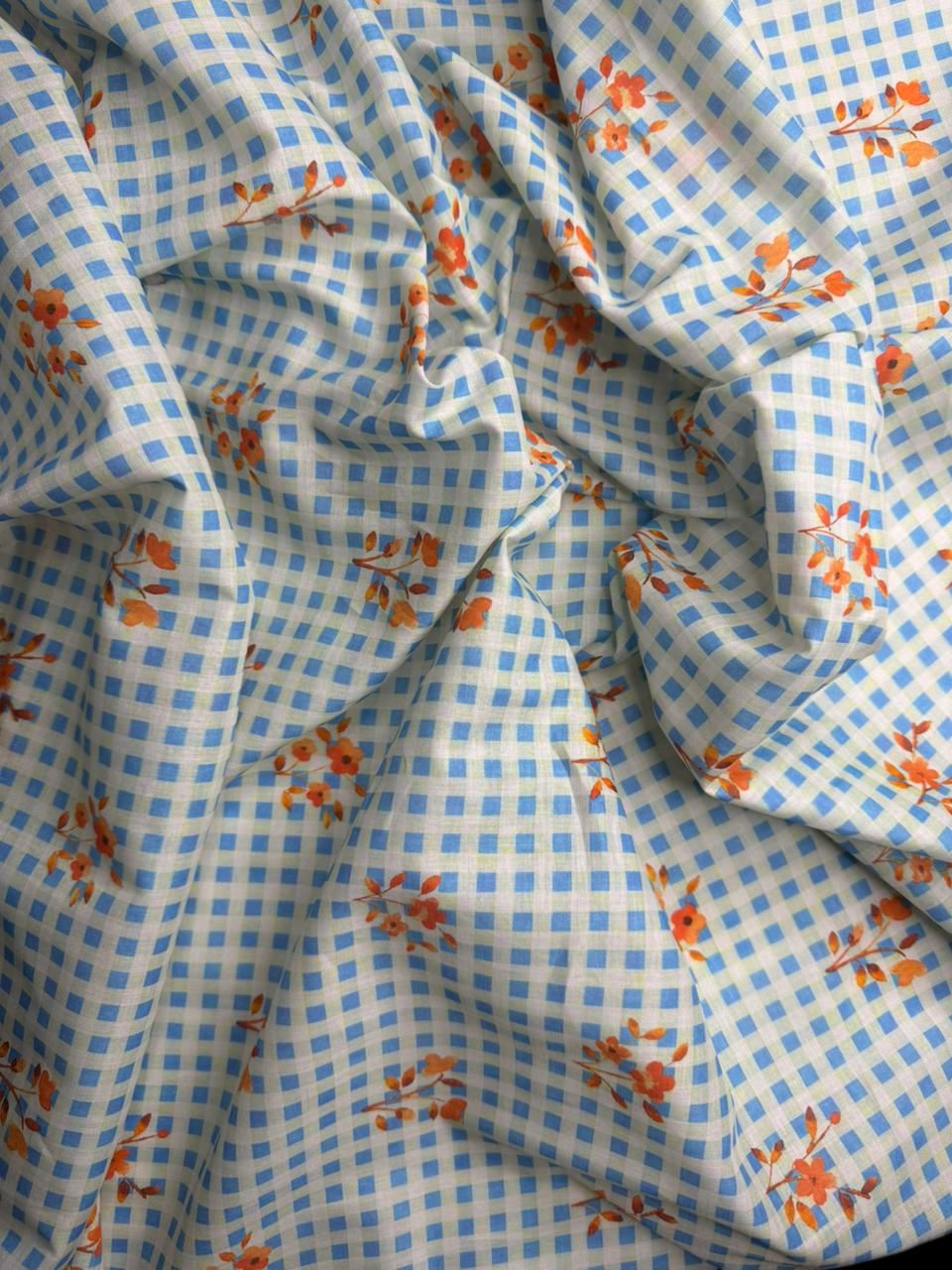 Close-up of checkered fabric with floral patterns in blue, white, and orange.