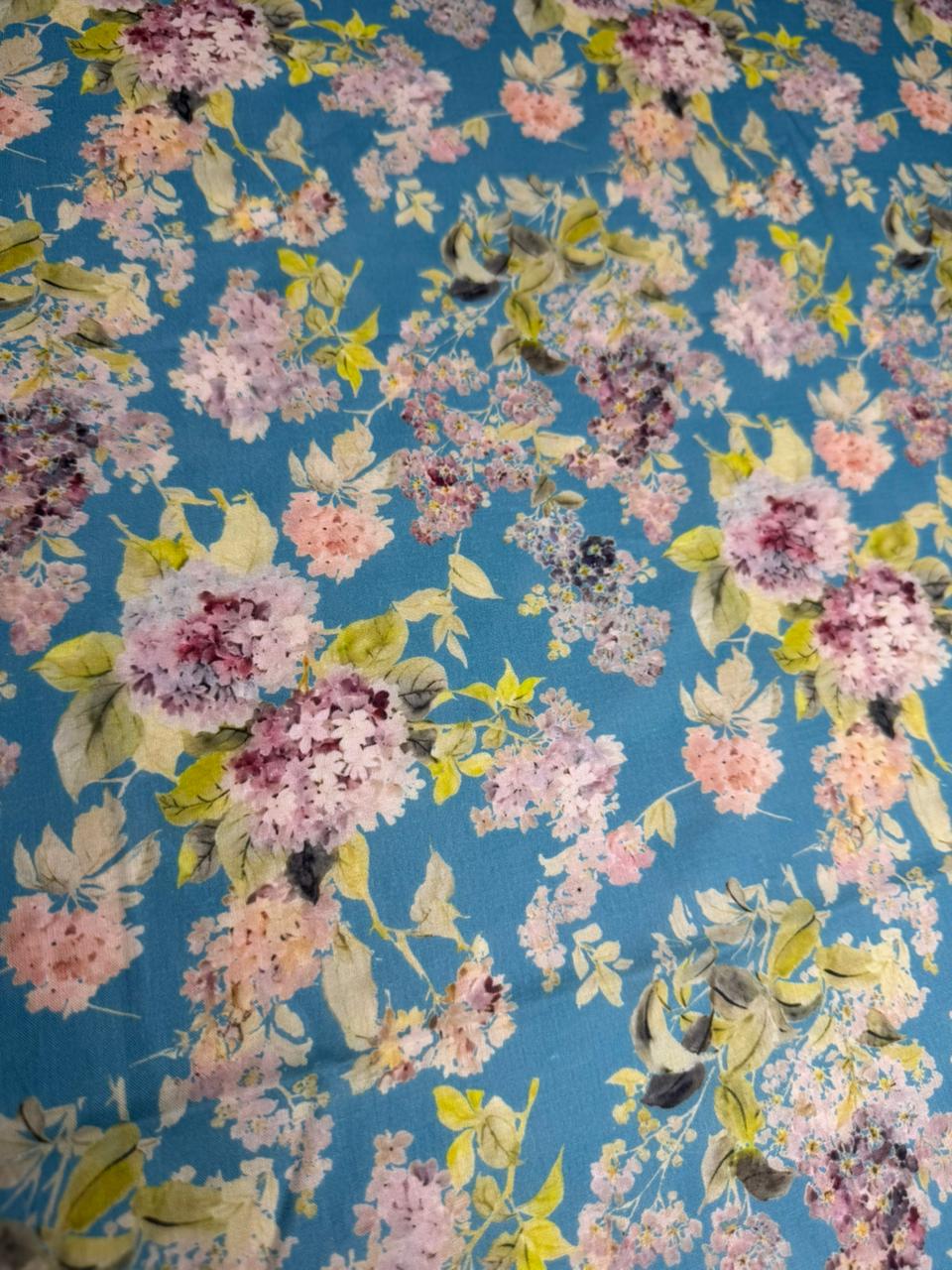 Floral patterned fabric with pink, yellow, and purple flowers on a blue background