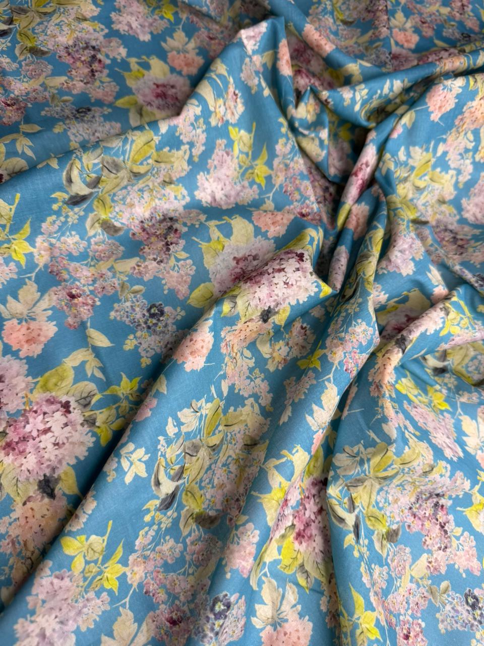 Floral fabric with pink, yellow, and green flowers on a blue background