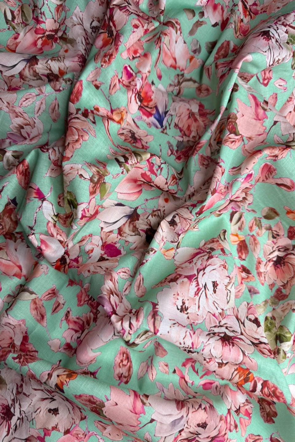 Floral fabric with pink and red flowers on a teal background