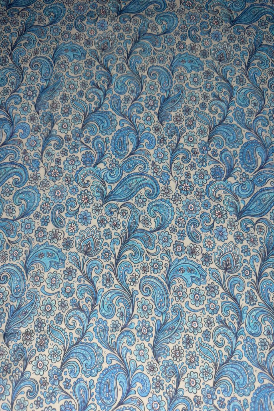 Blue paisley pattern on a textured fabric background