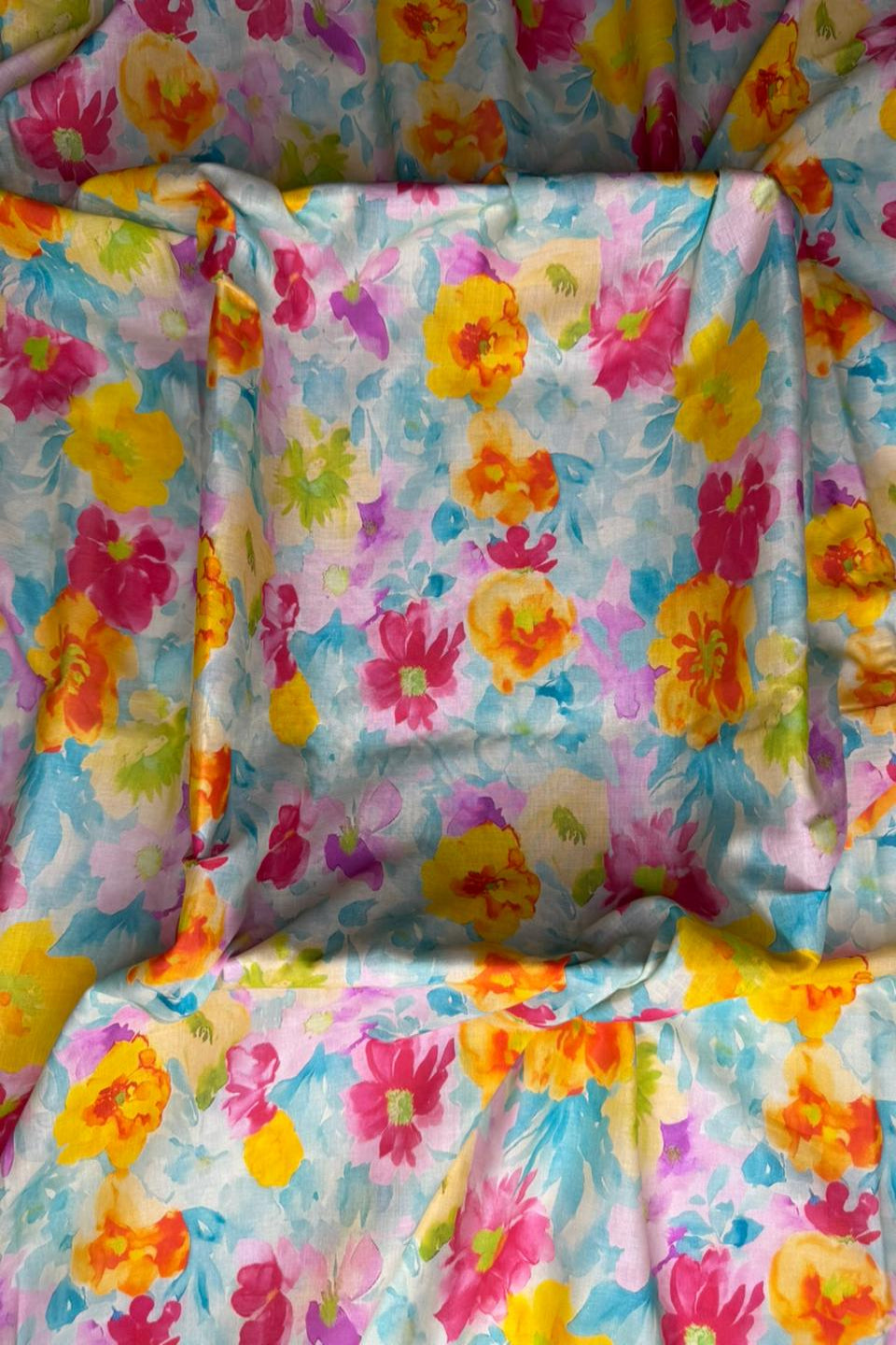 Colorful floral patterned fabric with a mix of pink, yellow, blue, and green flowers.