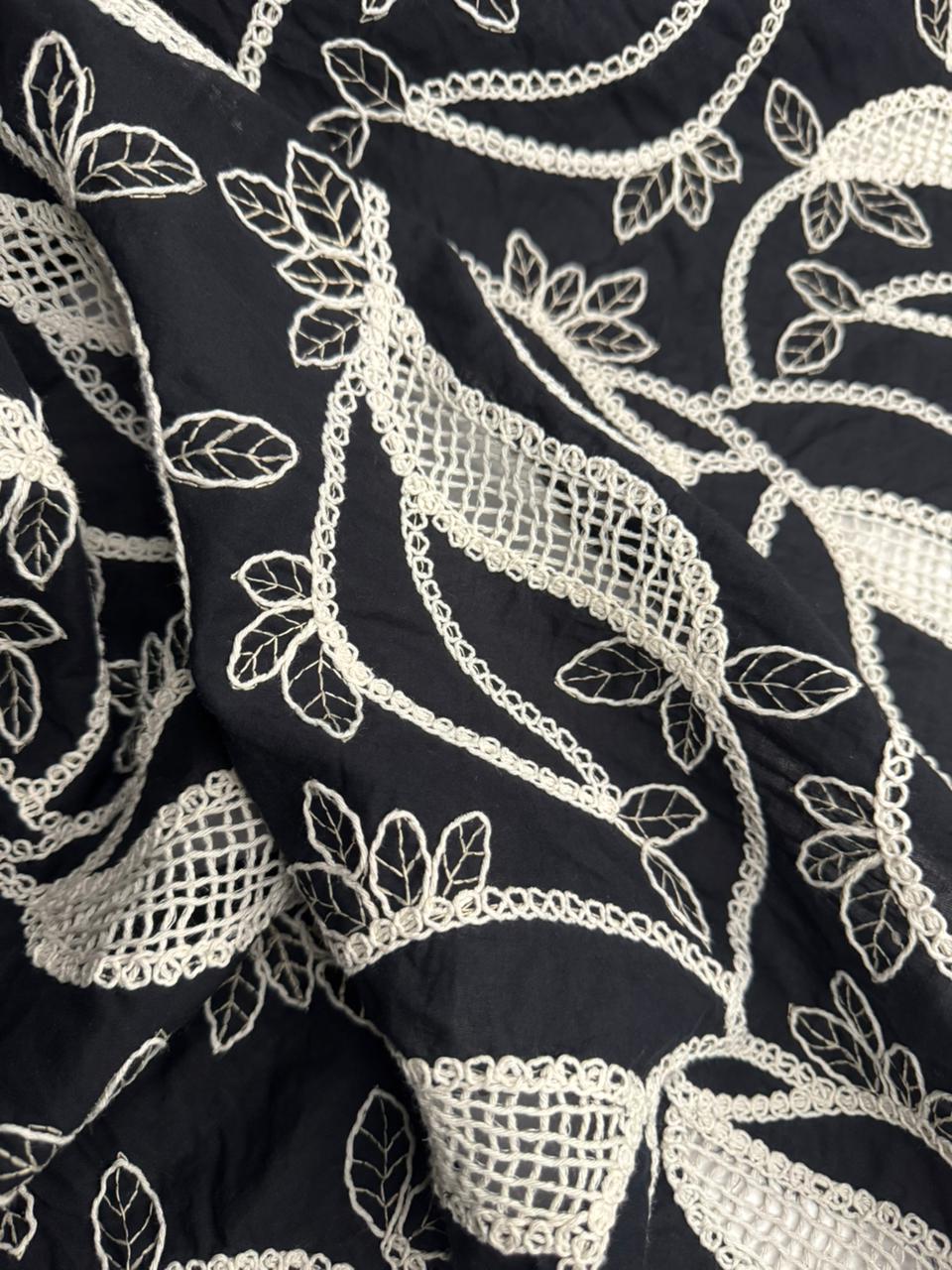 Close-up of black fabric with intricate white embroidery