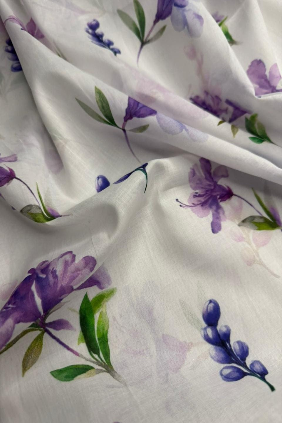 Floral fabric with purple flowers and green leaves on a white background