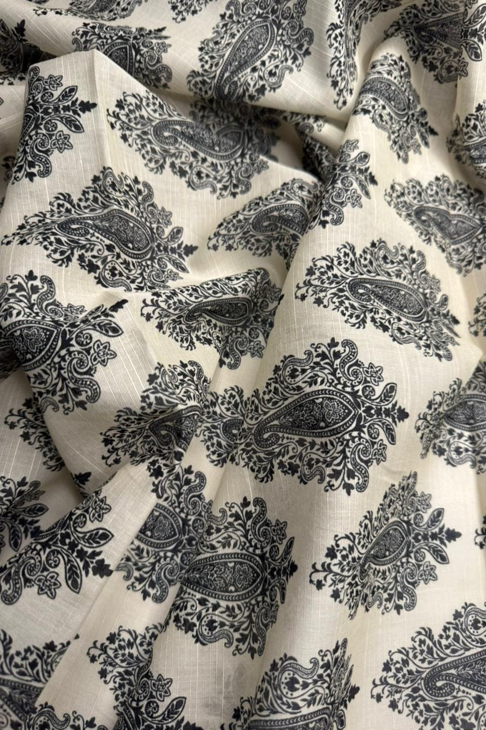 Close-up of black paisley pattern fabric on a beige background