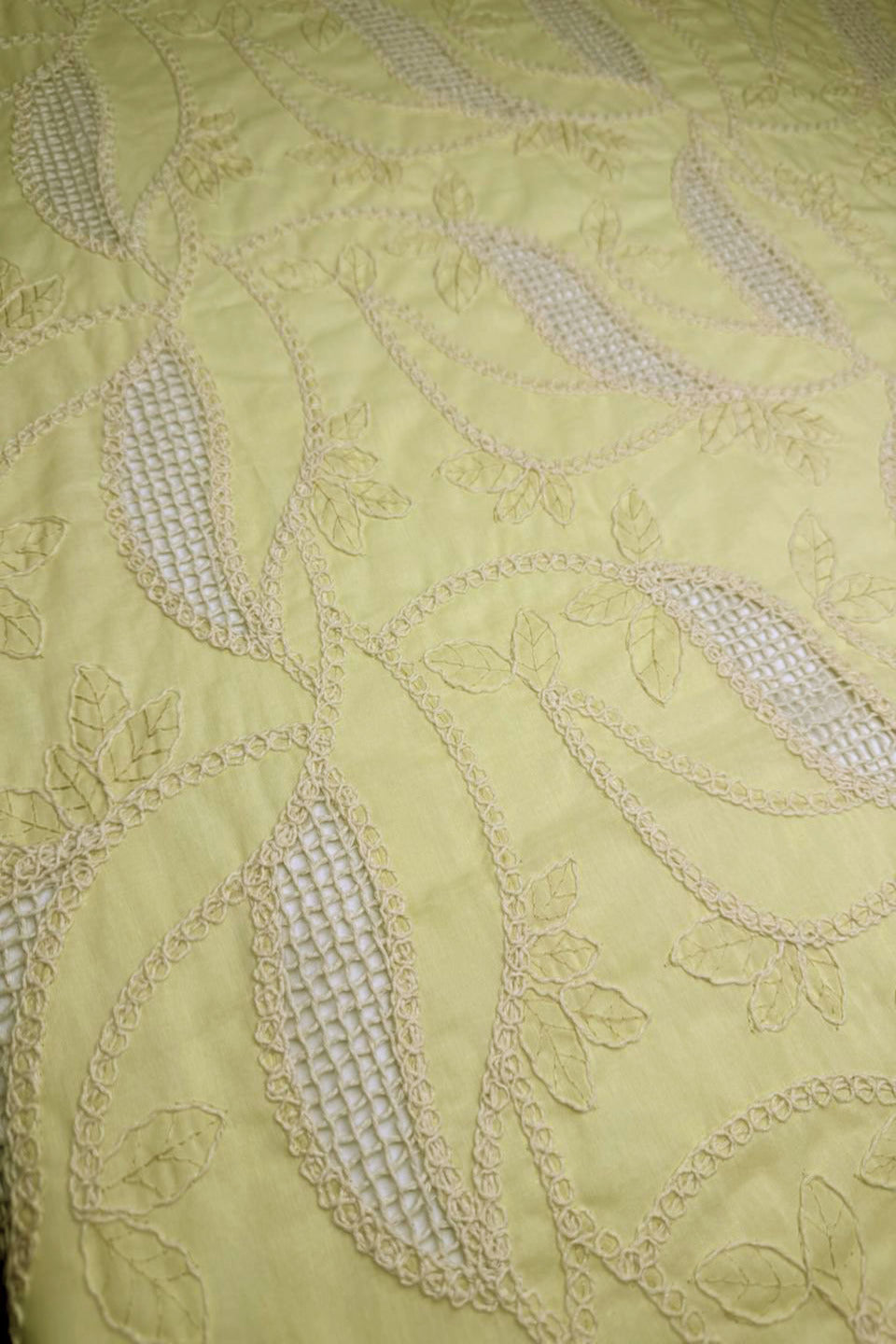 Close-up of embroidered fabric with leaf patterns on a light green background
