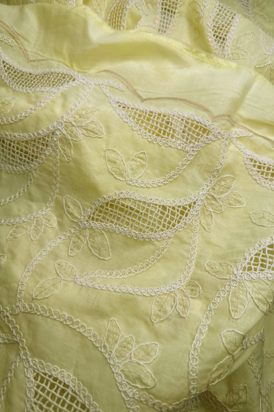 Close-up of light yellow fabric with intricate white embroidery