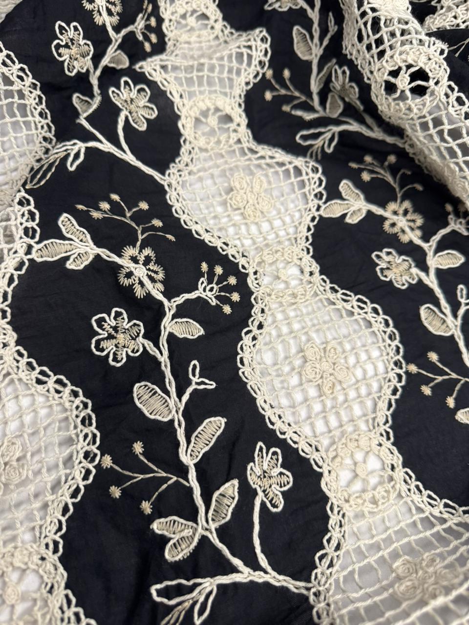 Close-up of black fabric with intricate white floral embroidery