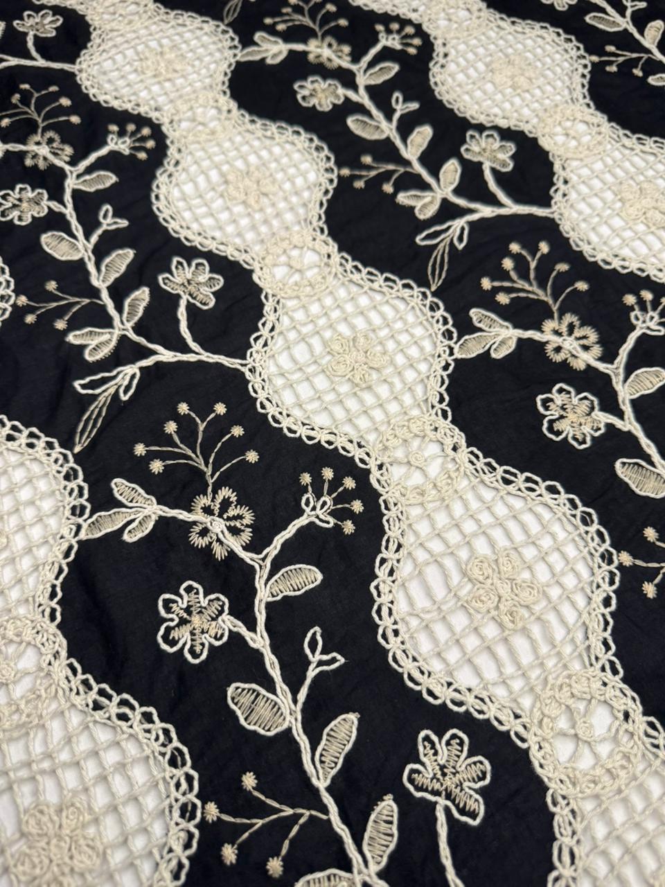 Close-up of black fabric with intricate white floral embroidery