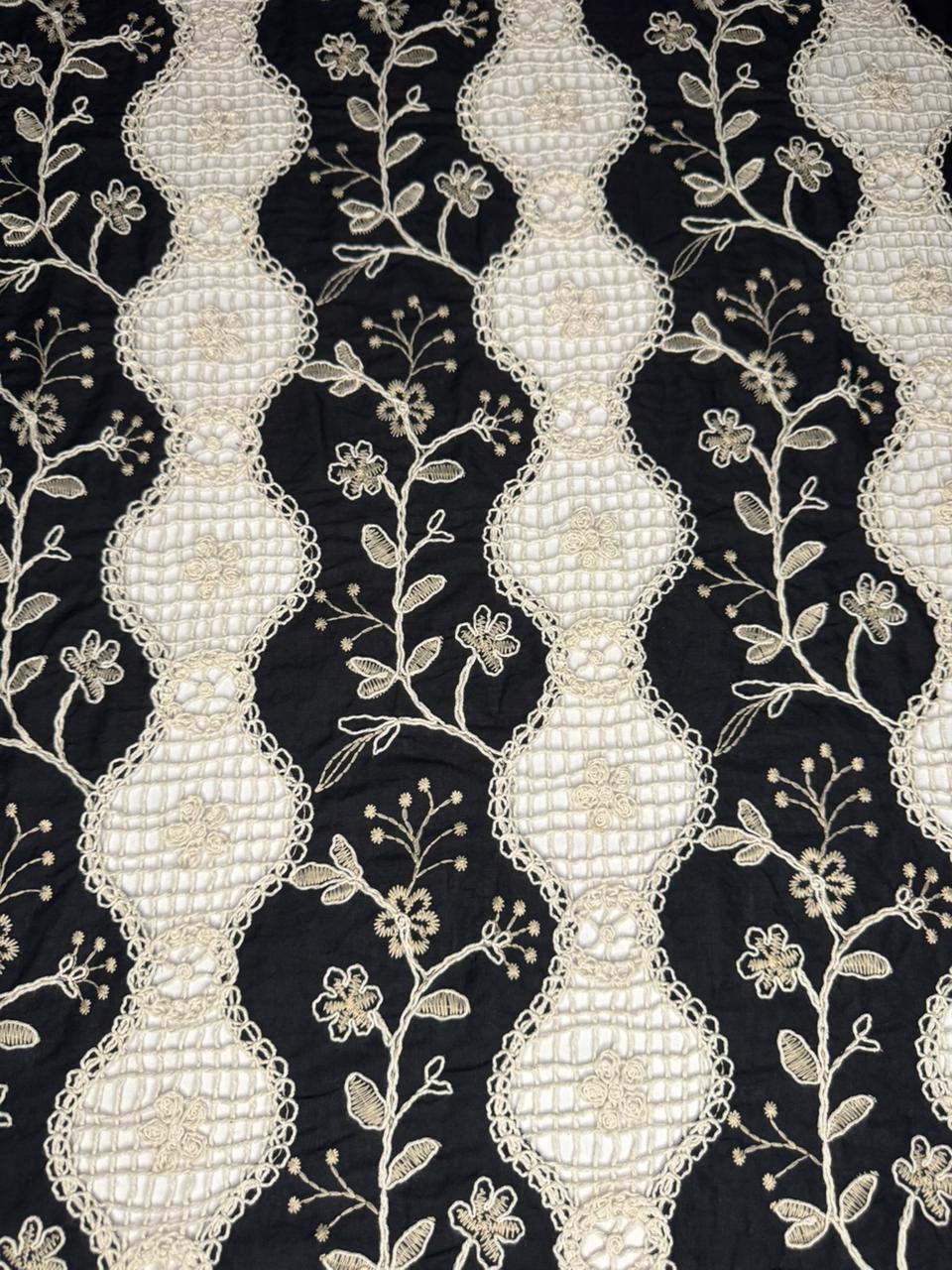 Decorative fabric with white embroidered patterns on a black background