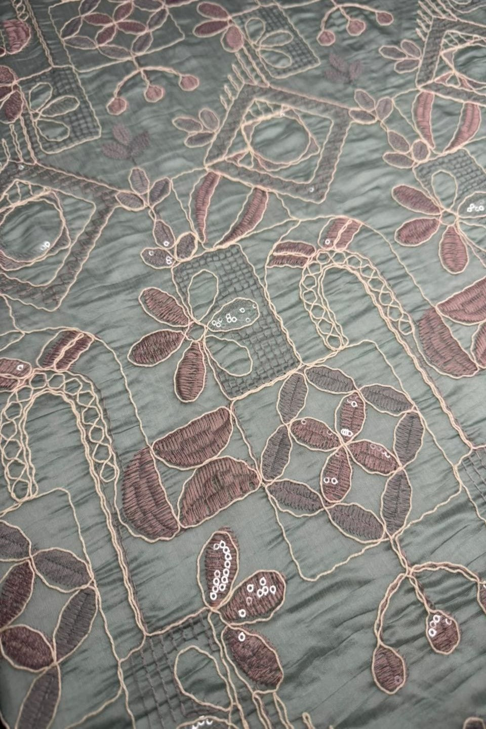 Close-up of intricate floral embroidery on fabric with a green background