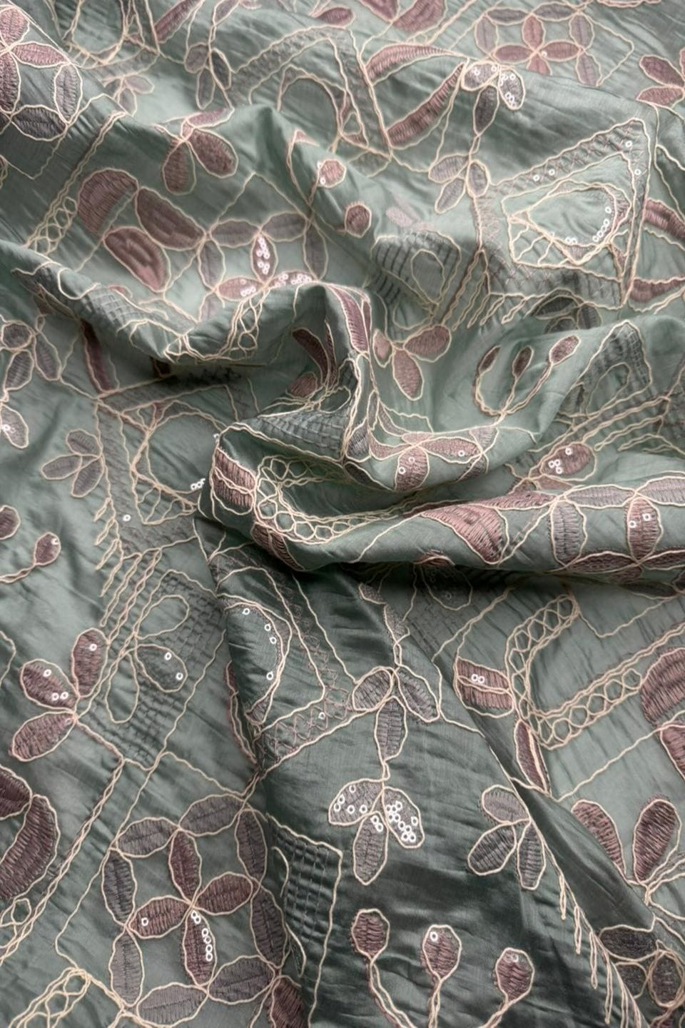 Textured fabric with floral embroidery on a green background