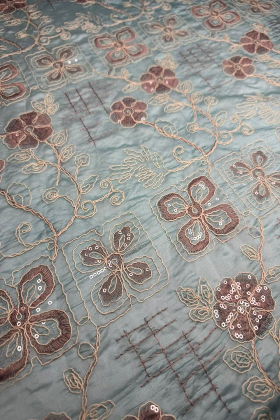 Close-up of floral embroidery on fabric with a blue background