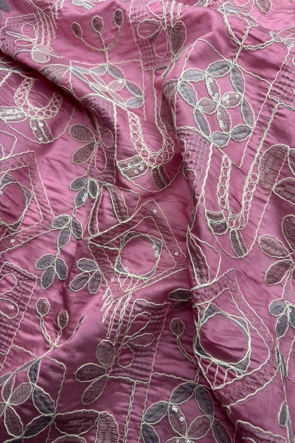 Close-up of pink fabric with intricate white floral patterns