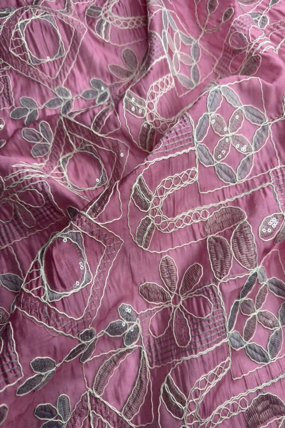 Close-up of pink fabric with intricate white floral patterns